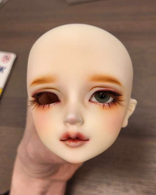 Female ball-jointed doll head with one blue-grey glass eye inserted.
