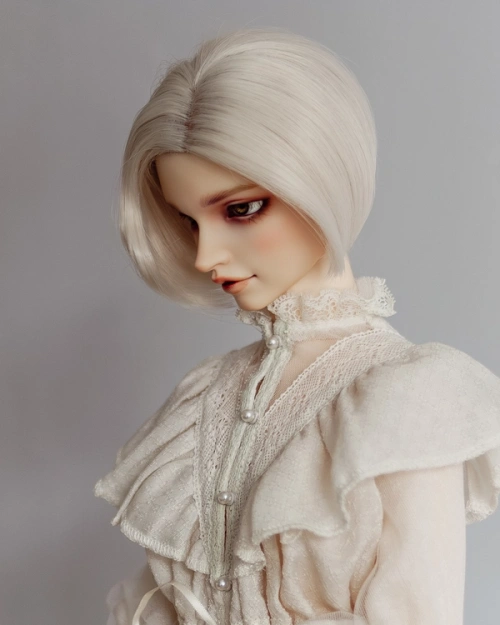 Side view of a male ball-jointed doll with cream hair, wearing a frilly, lacy cream robe.