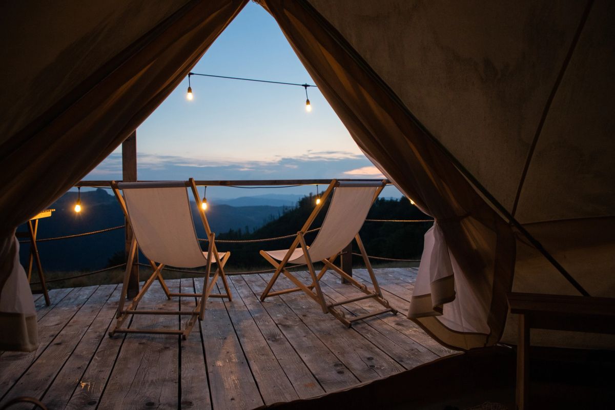 Two chairs set atop a wood deck with a canopy overhead.