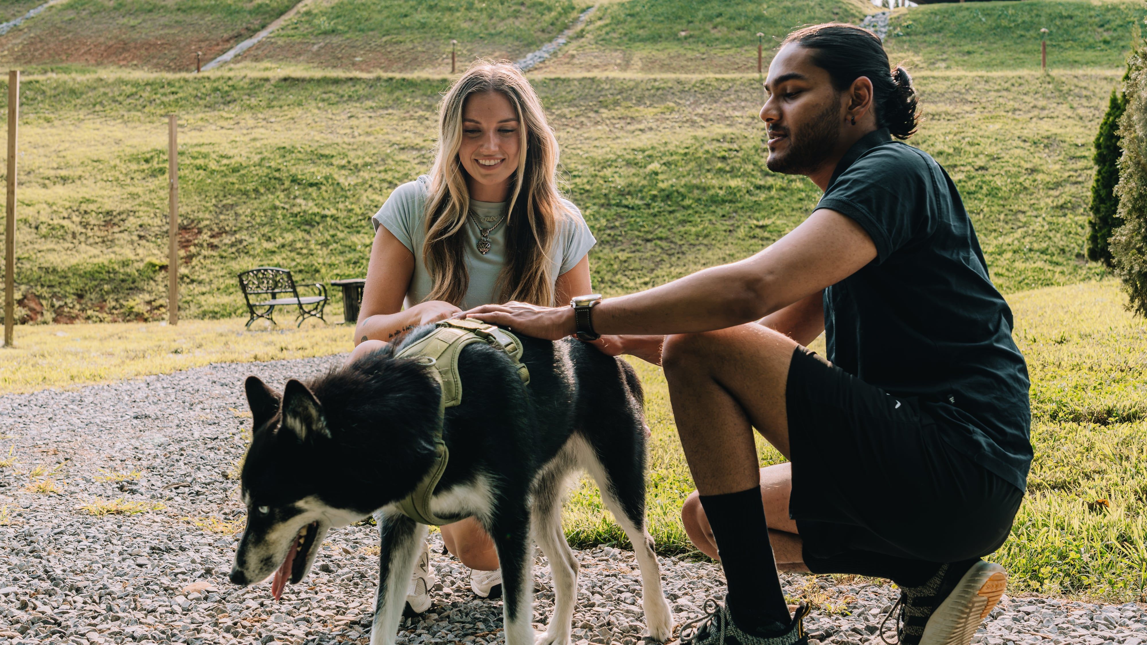 A couple crouched together petting their dog beside the trail at Sojourn Lodging