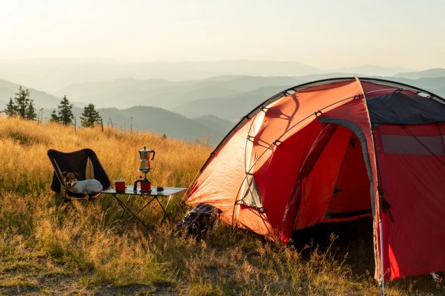 Photo of an orange tent set up in the mountains.