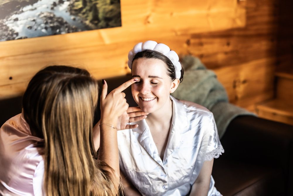 Bride smiling while having makeup applied inside a Sojourn Lodging tiny home on her wedding morning