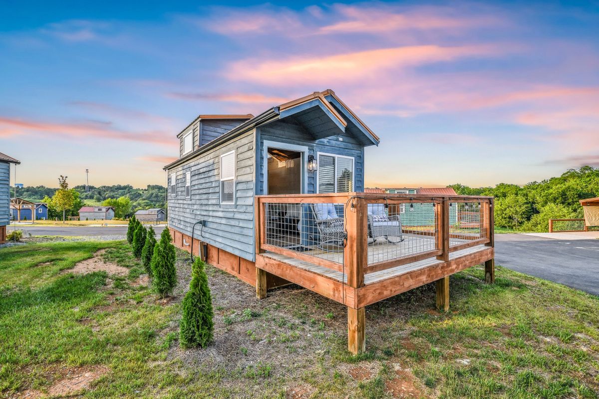 Sojourn blue tiny home exterior at sunset with private deck and mountain views beyond
