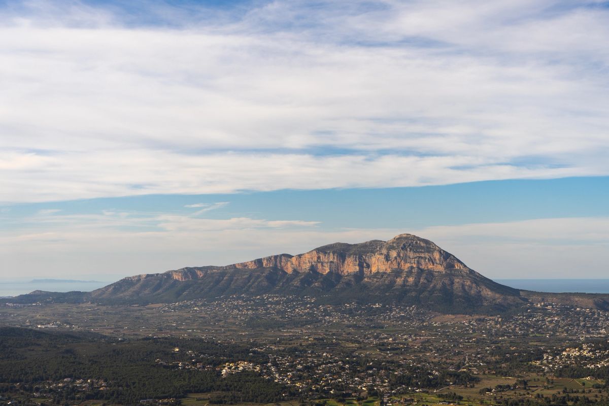 Mountain from a far shown underneath a blue and white sky.