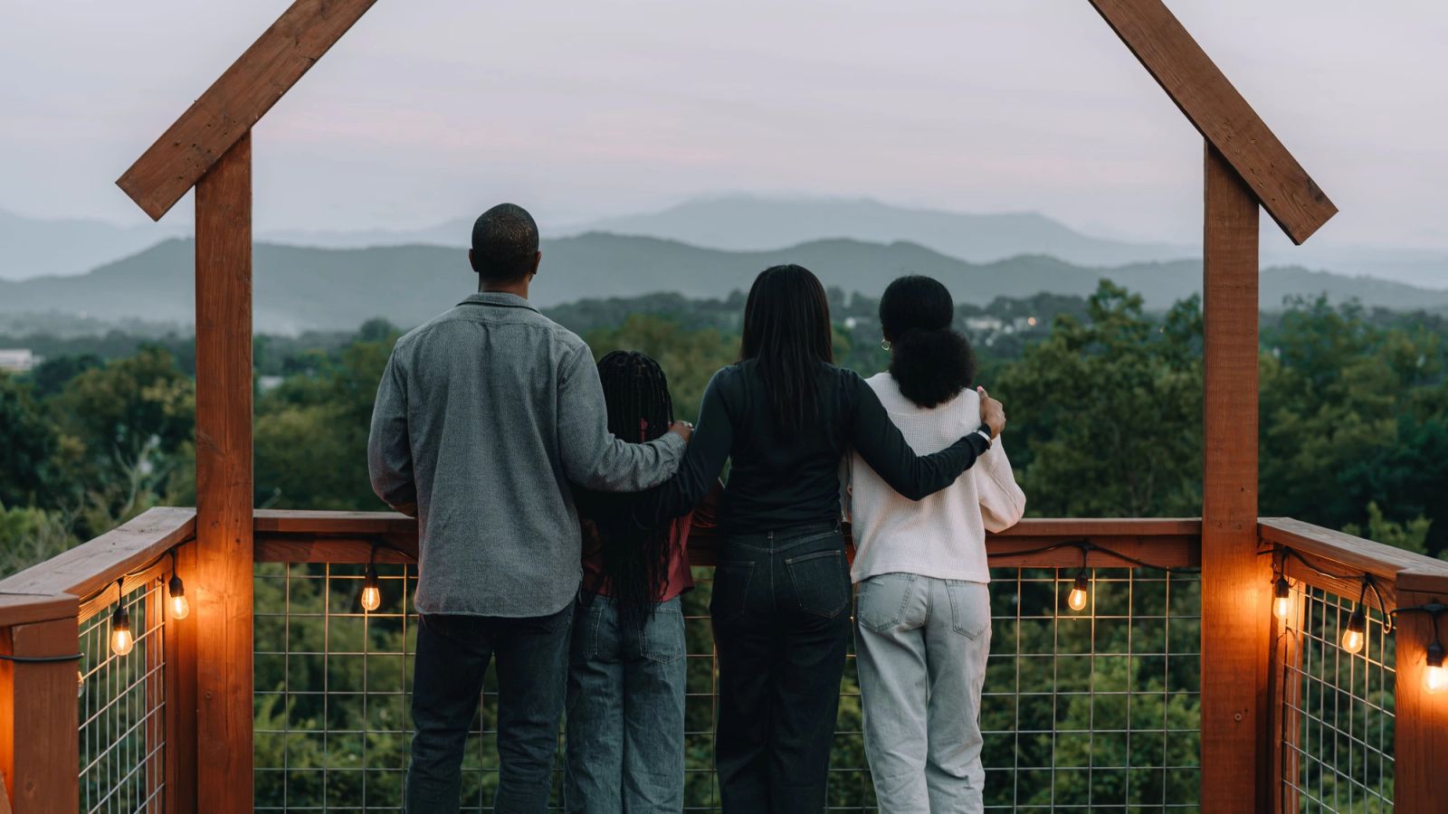 A family of four at the Observation Deck rail looking out over the Smoky Mountains at dusk