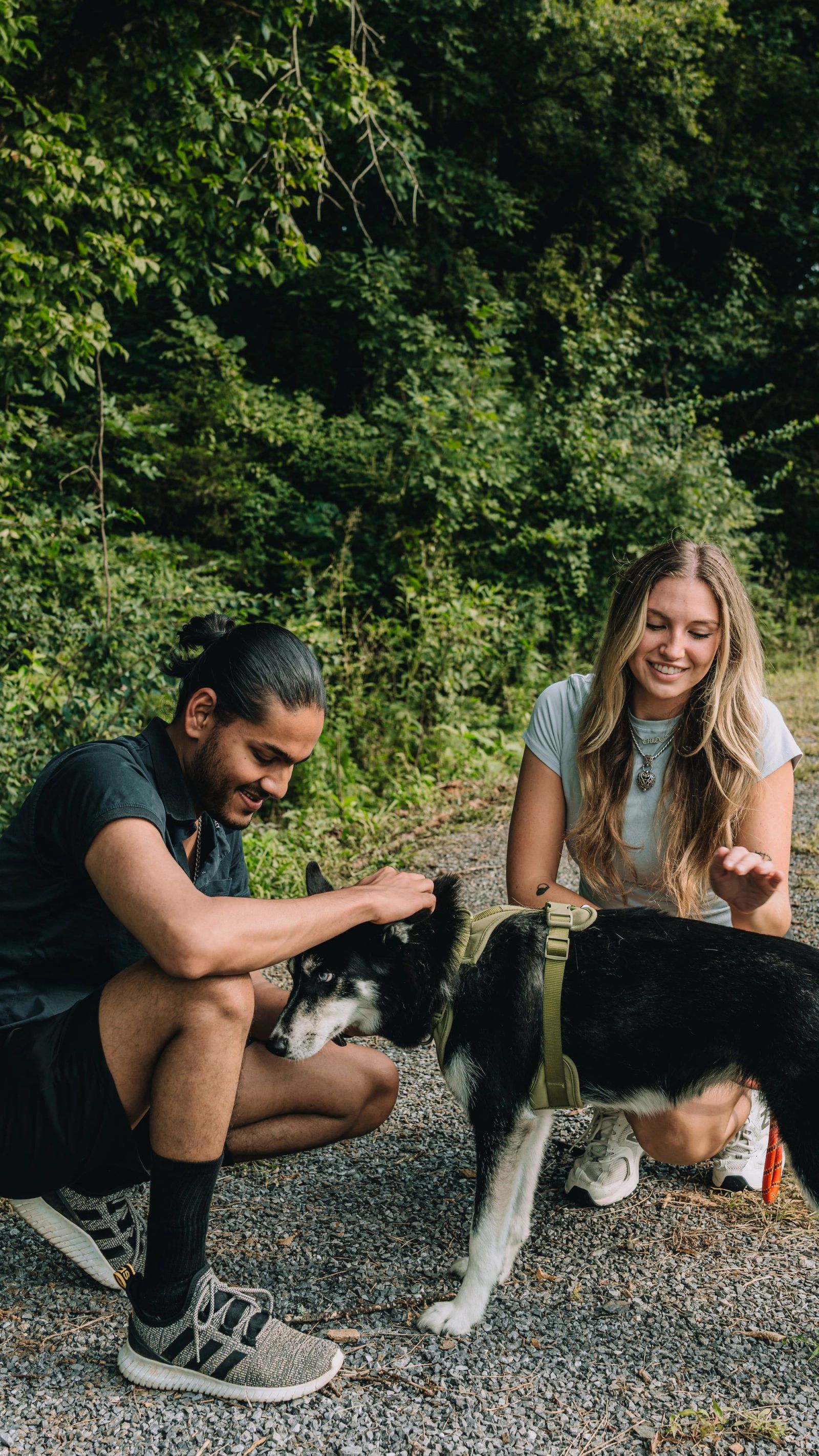 A couple crouching to greet their dog on the gravel path at Sojourn Lodging