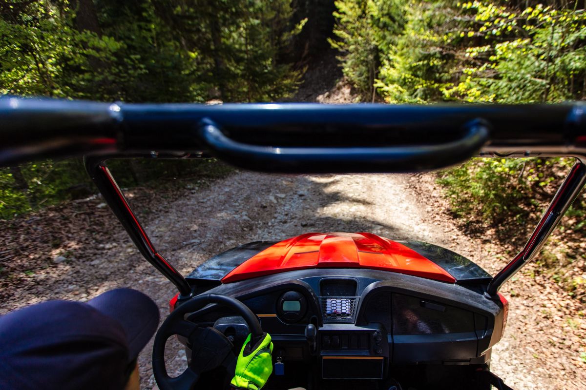 POV photo of a person driving a red UTV.