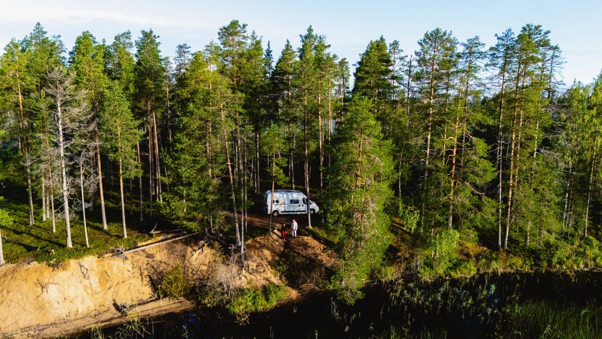 White RV driving between trees.