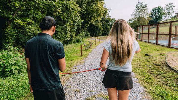 A couple walking their dog along the gravel walking trail at Sojourn Lodging