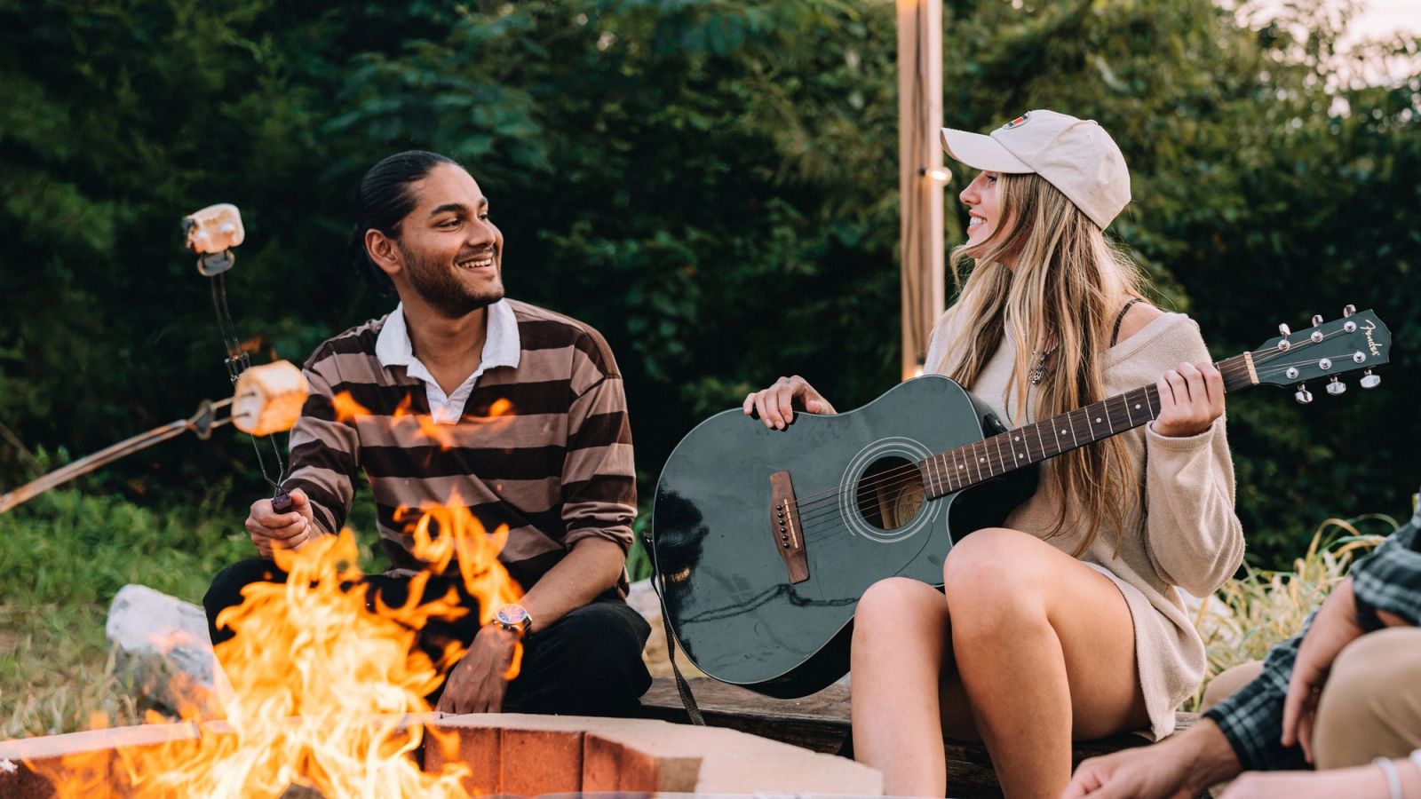 A guest playing guitar while a friend roasts a marshmallow over the Sunset Point firepit