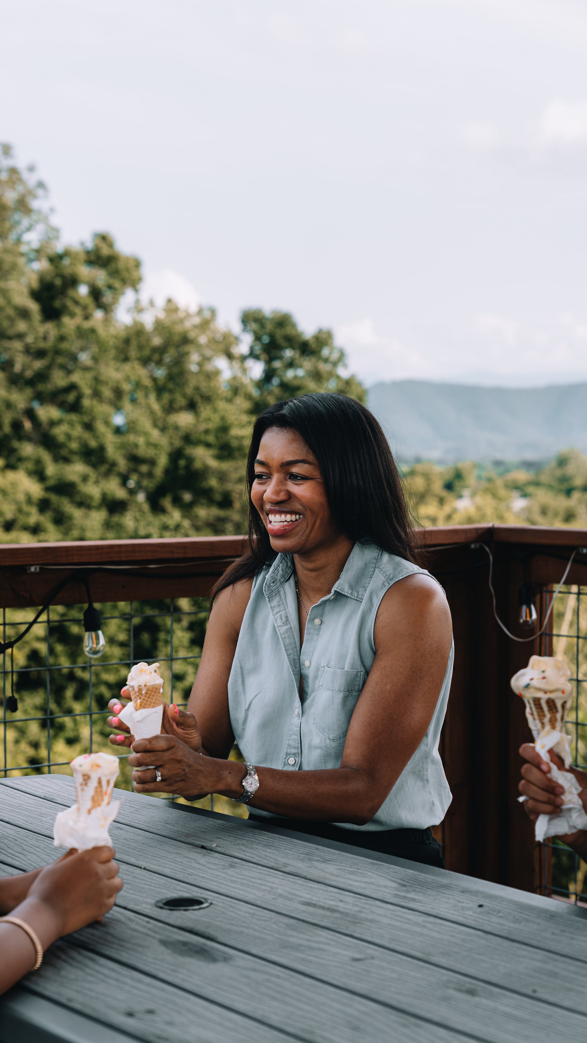 A guest enjoying ice cream at the Observation Deck table with the mountains behind
