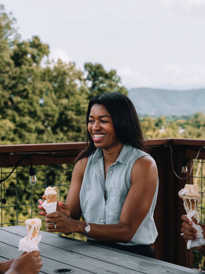 A guest enjoying ice cream at the Observation Deck table with the mountains behind