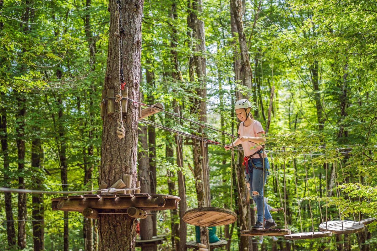 Woman walking across wooden steps/bridge in the woods.