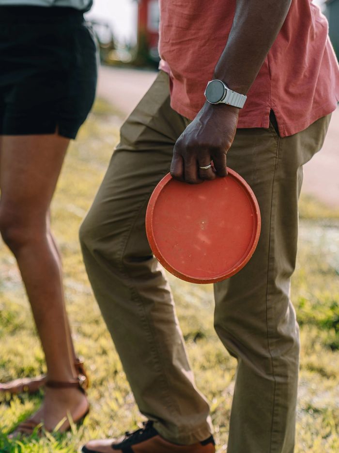 Detail of a guest holding a red disc golf disc at their side on the lawn at Sojourn Lodging