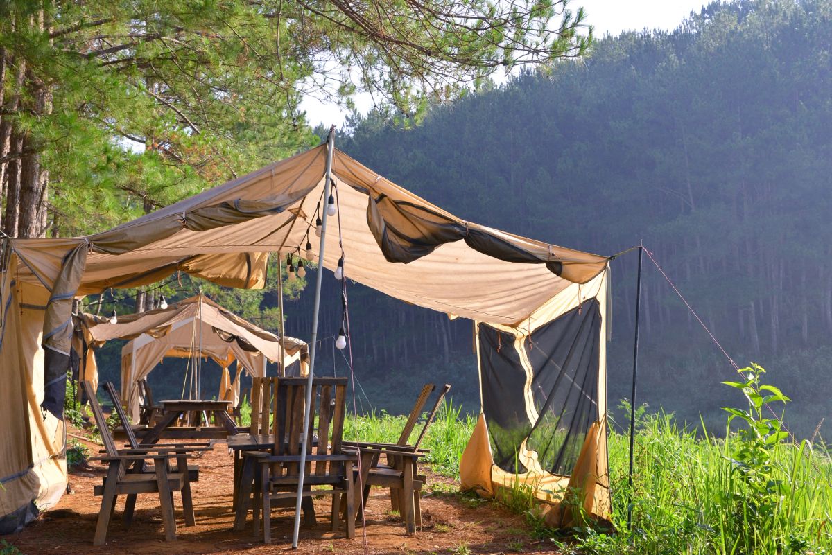 Safari tent accommodation set up underneath a green mountain view.