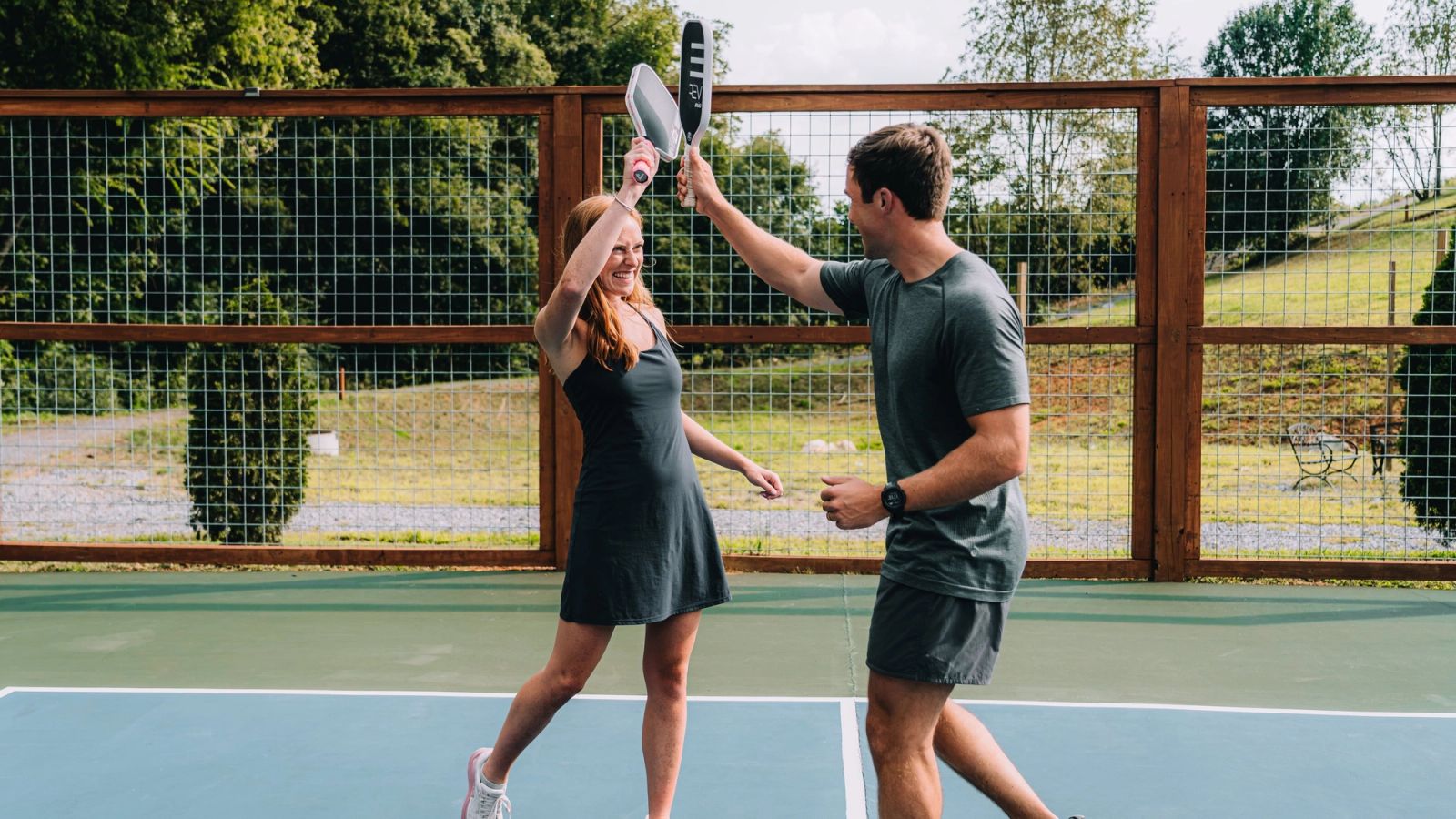 Two players touching paddles above the net on the pickleball court at Sojourn Lodging