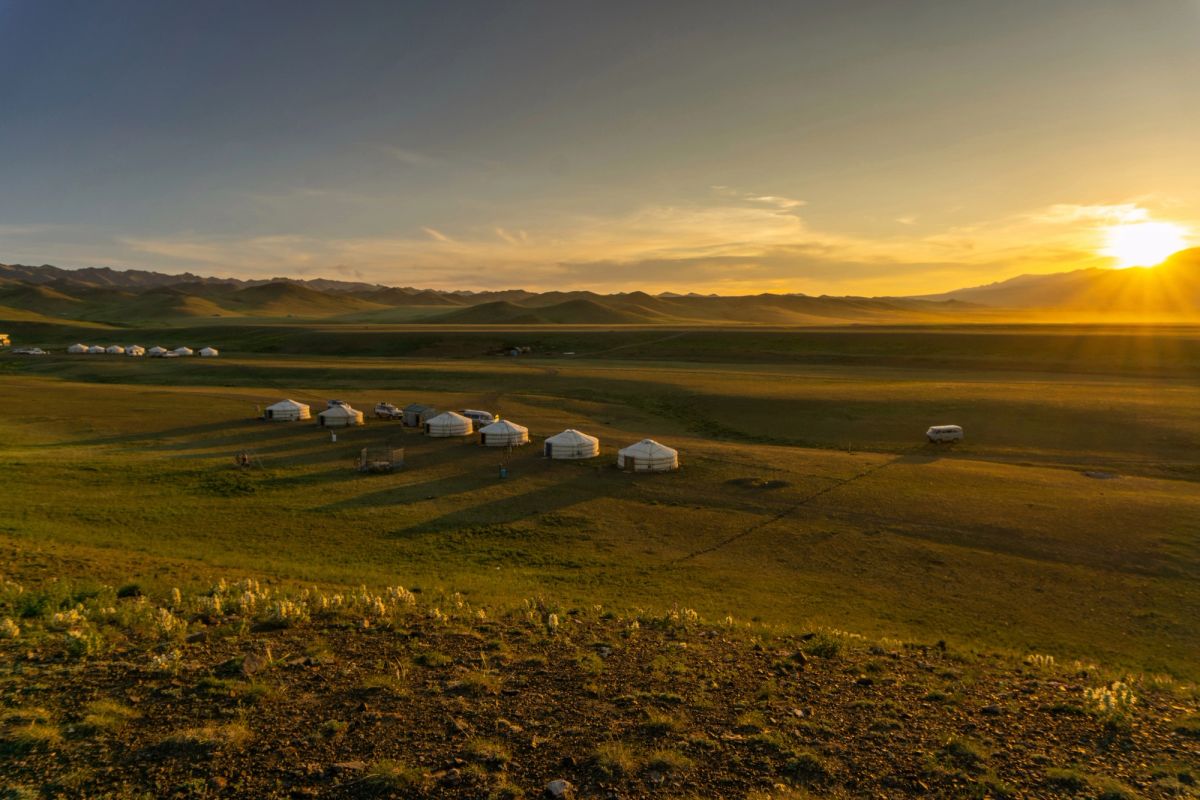 Far away shot of a line of white yurts stationed in the mountains.