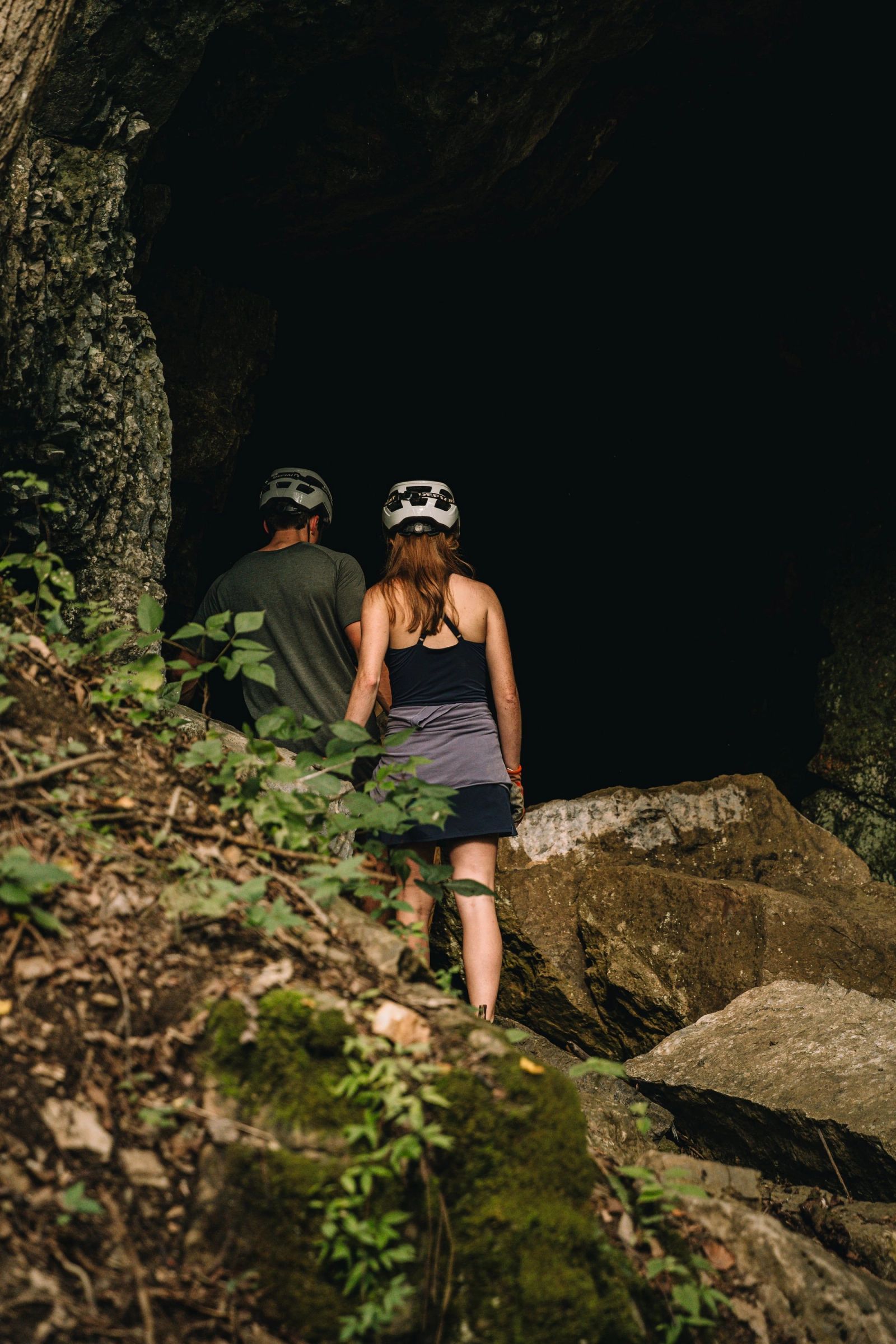 A couple standing at the entrance of the Sojourn Grotto cave, looking into the dark