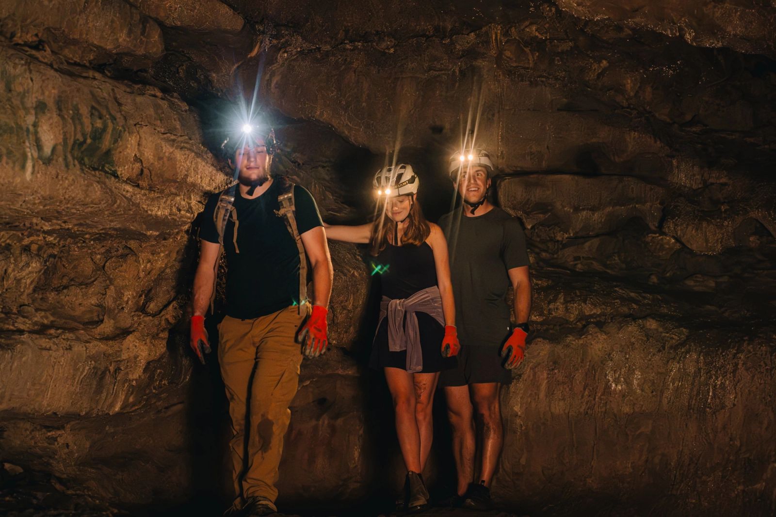 Three cavers with headlamps standing together in a chamber of the Sojourn Grotto