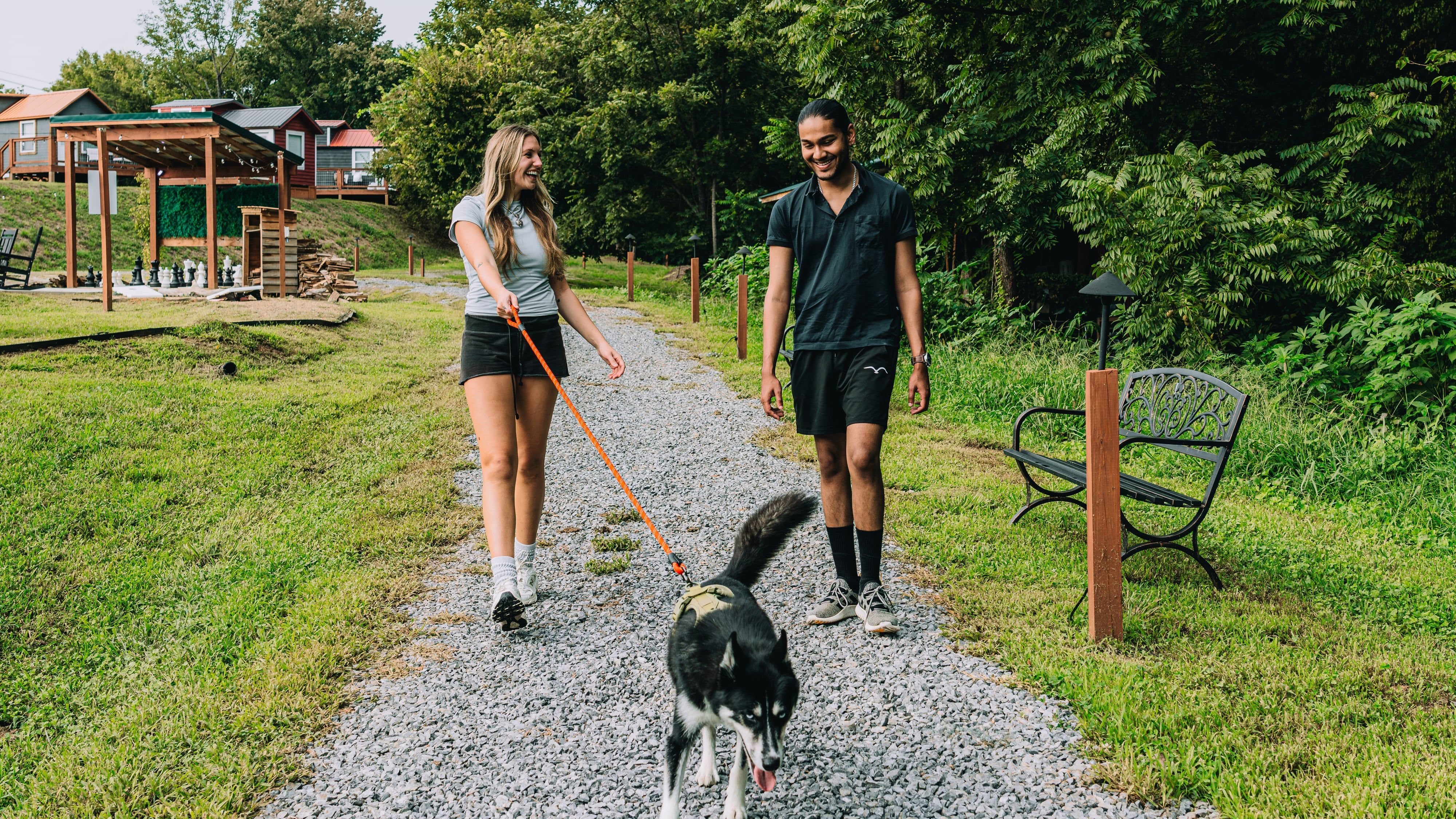 A couple walking their dog on the gravel trail past a trailside bench at Sojourn Lodging