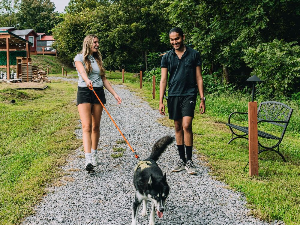 A couple walking their dog on the gravel trail past a trailside bench at Sojourn Lodging
