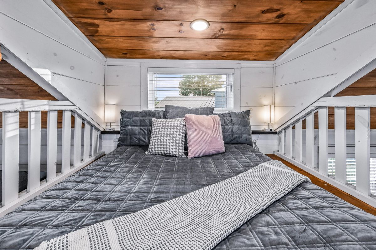 Cozy sleeping loft in a Sojourn tiny home with vaulted wood ceiling and plush bedding