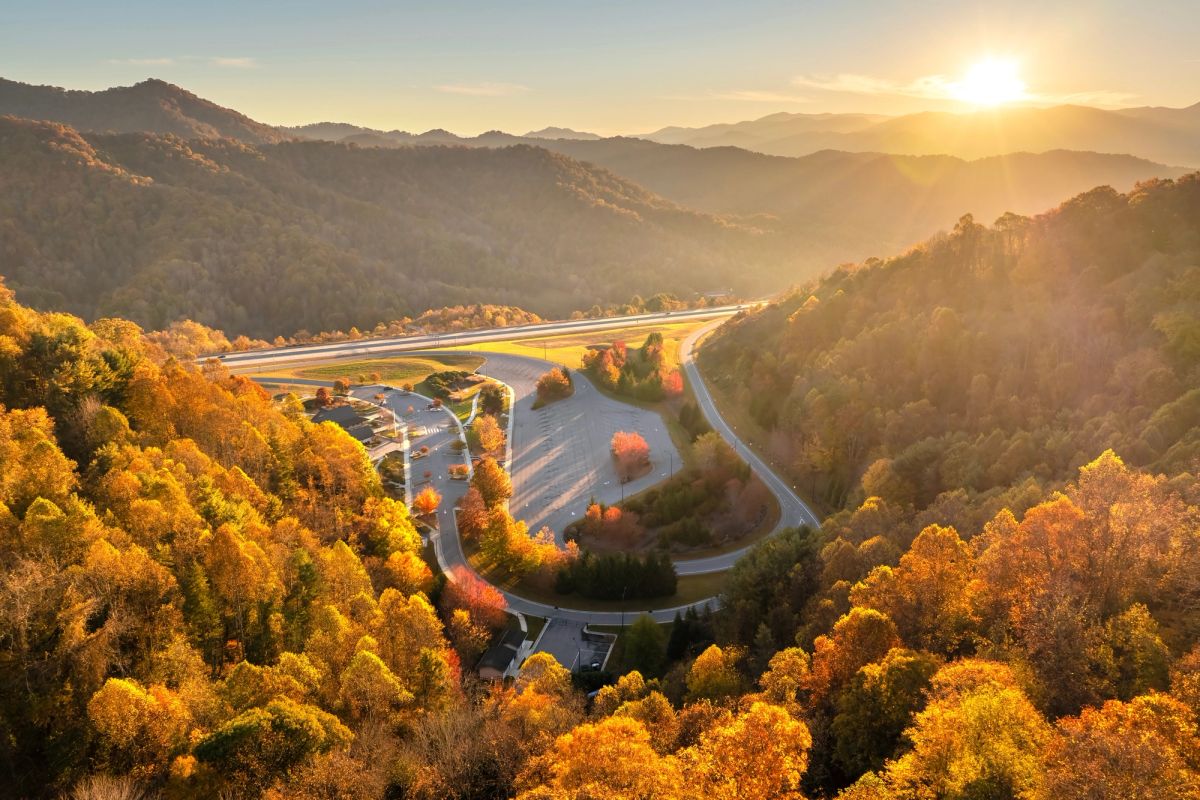 Sunset view of roads between mountains and trees.