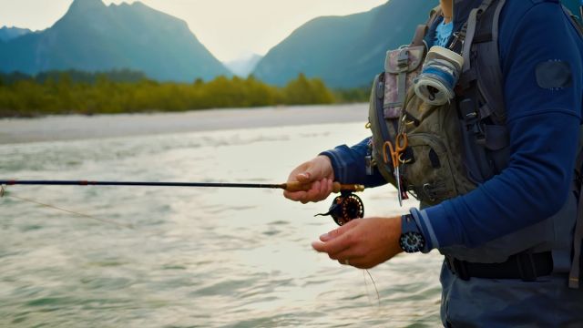 Man fly fishing with a mountain background.