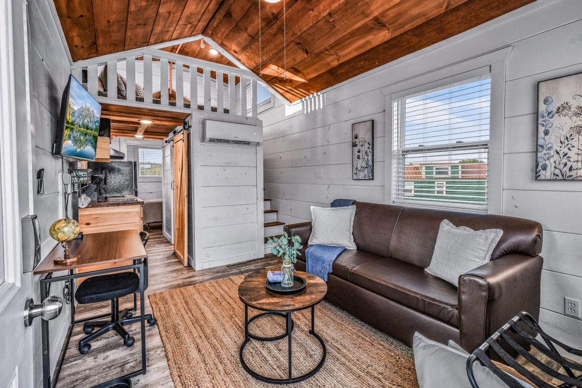 Sojourn tiny home open door revealing loft interior, living space, and private deck beyond