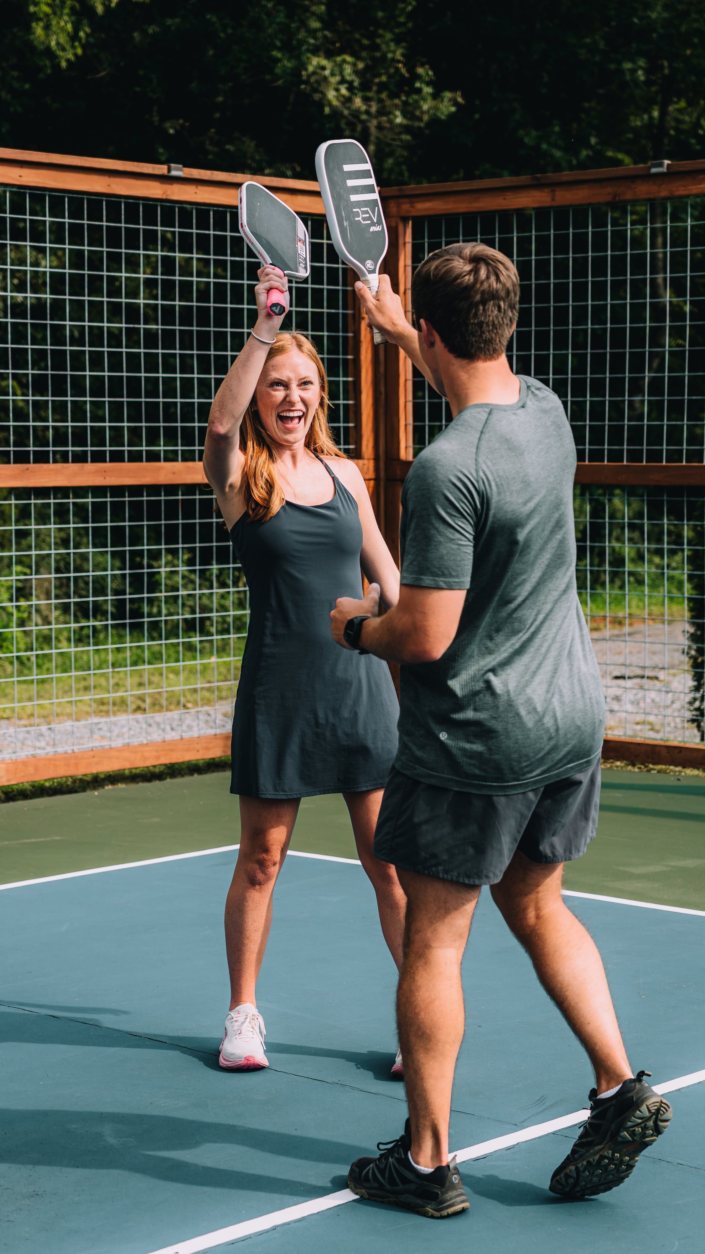 Two players raising their paddles in celebration on the pickleball court at Sojourn Lodging