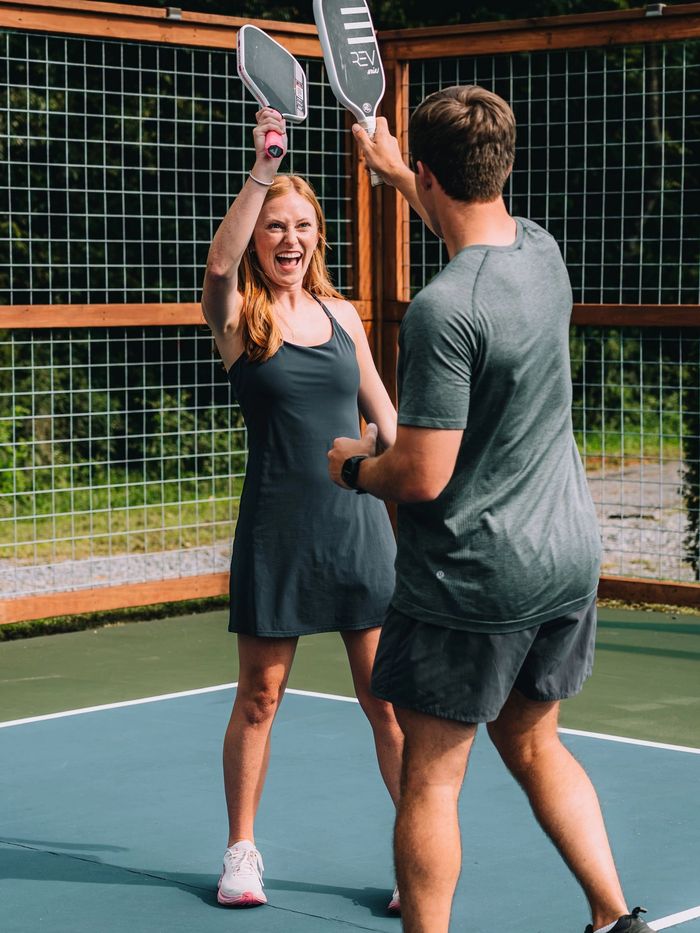 Two players raising their paddles in celebration on the pickleball court at Sojourn Lodging