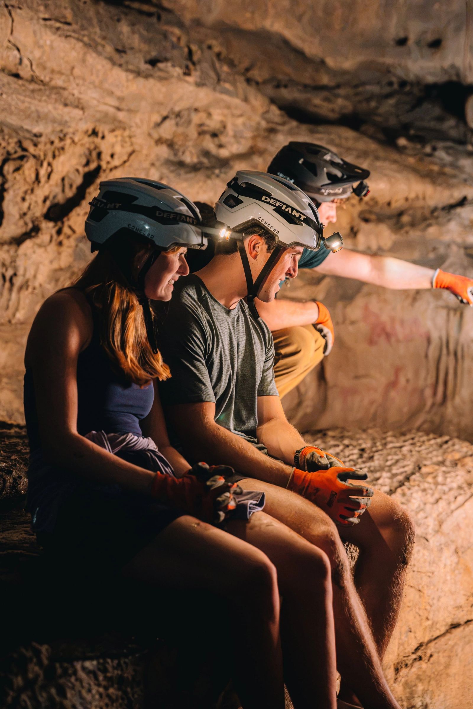 A guide gesturing while guests sit on the ledge listening inside the Sojourn Grotto