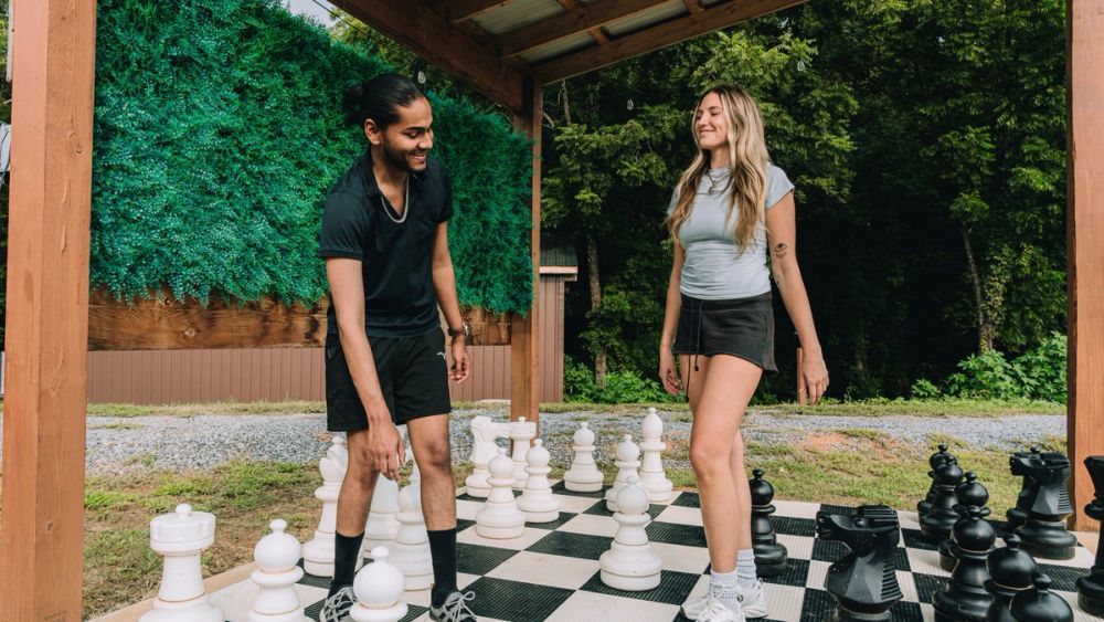 Two guests playing on the life-size chess board beneath the gazebo at Sojourn Lodging