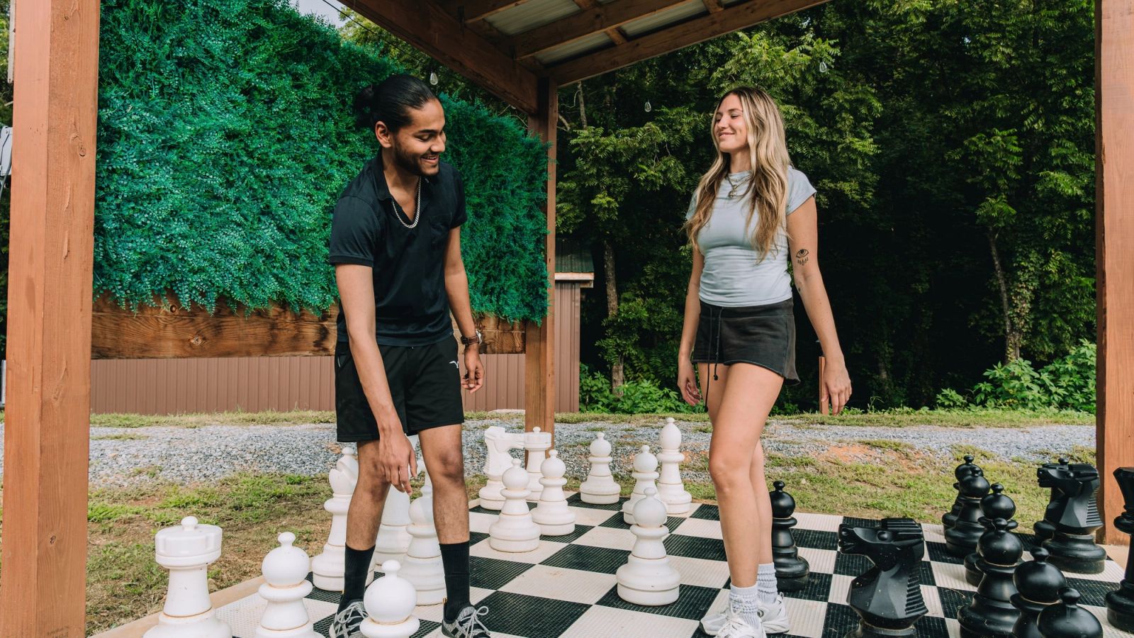 Two guests playing on the life-size chess board beneath the gazebo at Sojourn Lodging