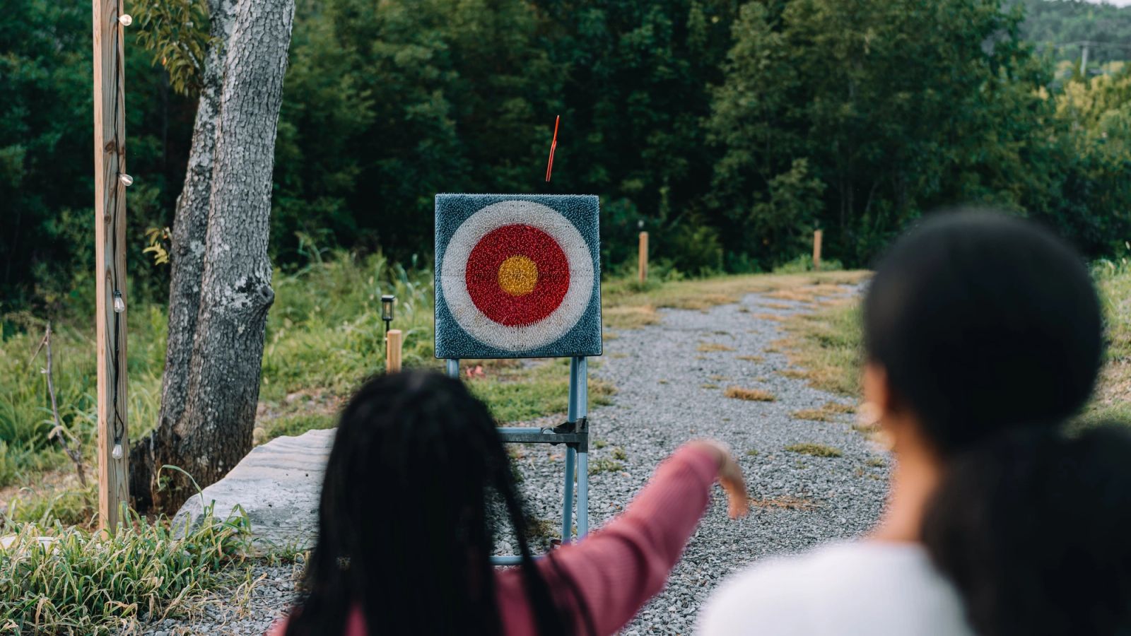 Two guests lining up a throw at the axe-throwing target down the gravel lane
