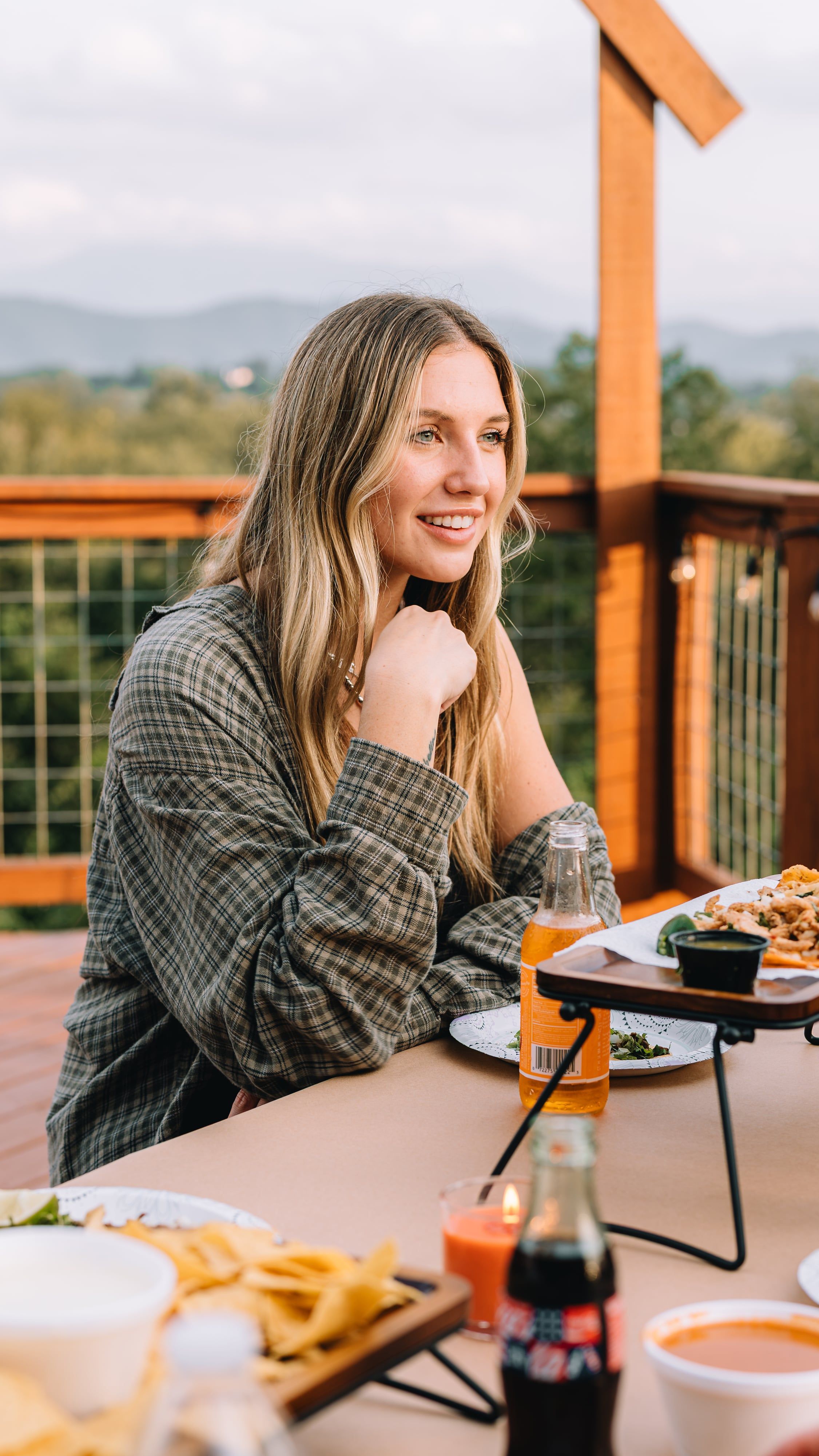 A guest at the Observation Deck dinner table with the mountain ridgeline behind at golden hour
