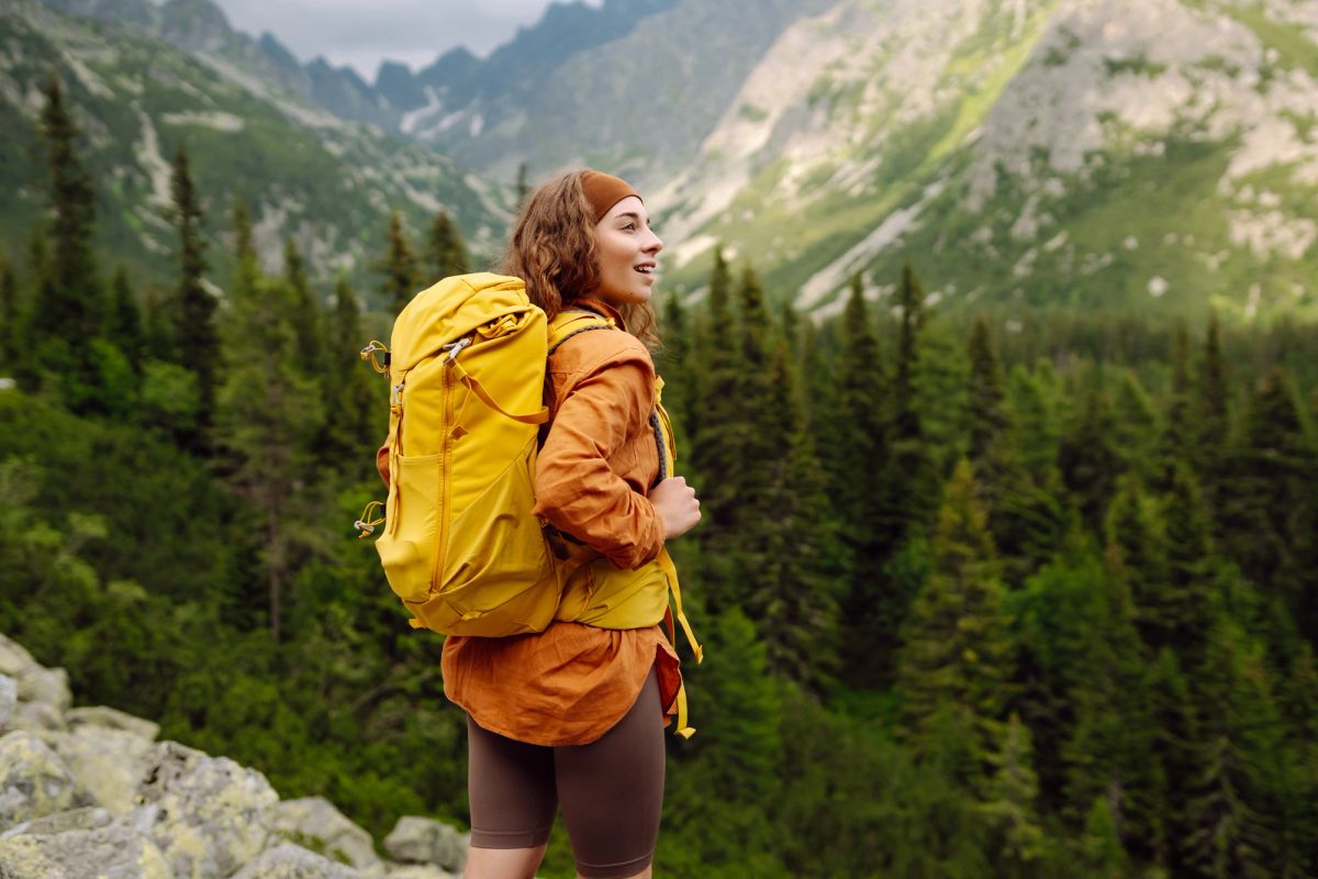 Woman smiling while standing on a mountain top.