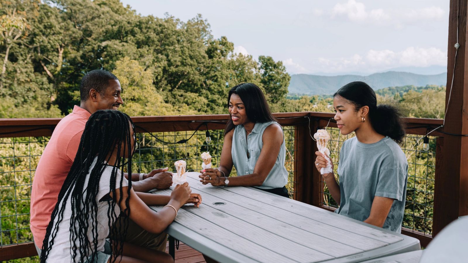 Four friends sharing ice cream at the Observation Deck table with mountain views