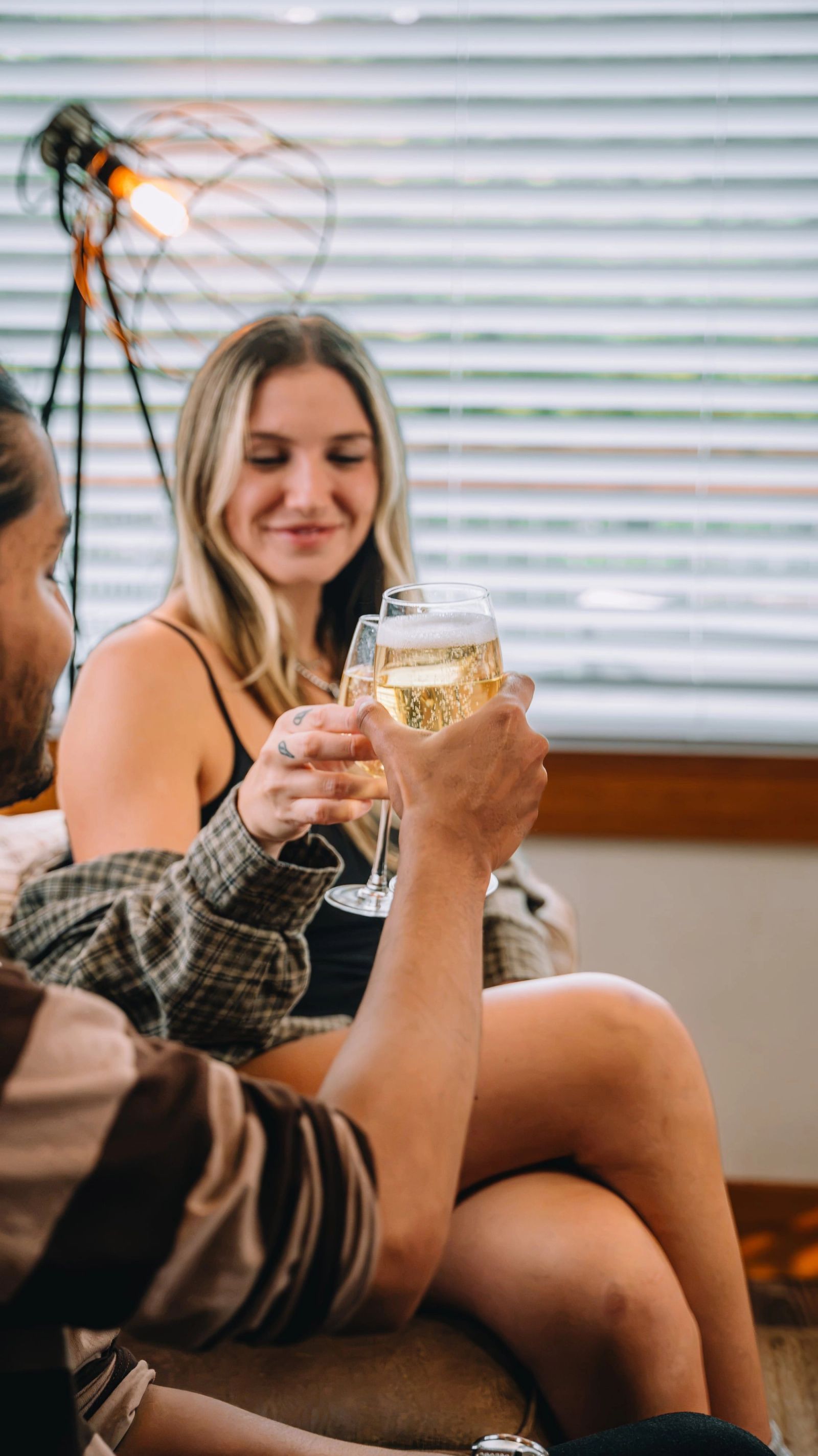 A couple clinking glasses on the sofa of their tiny home at Sojourn Lodging