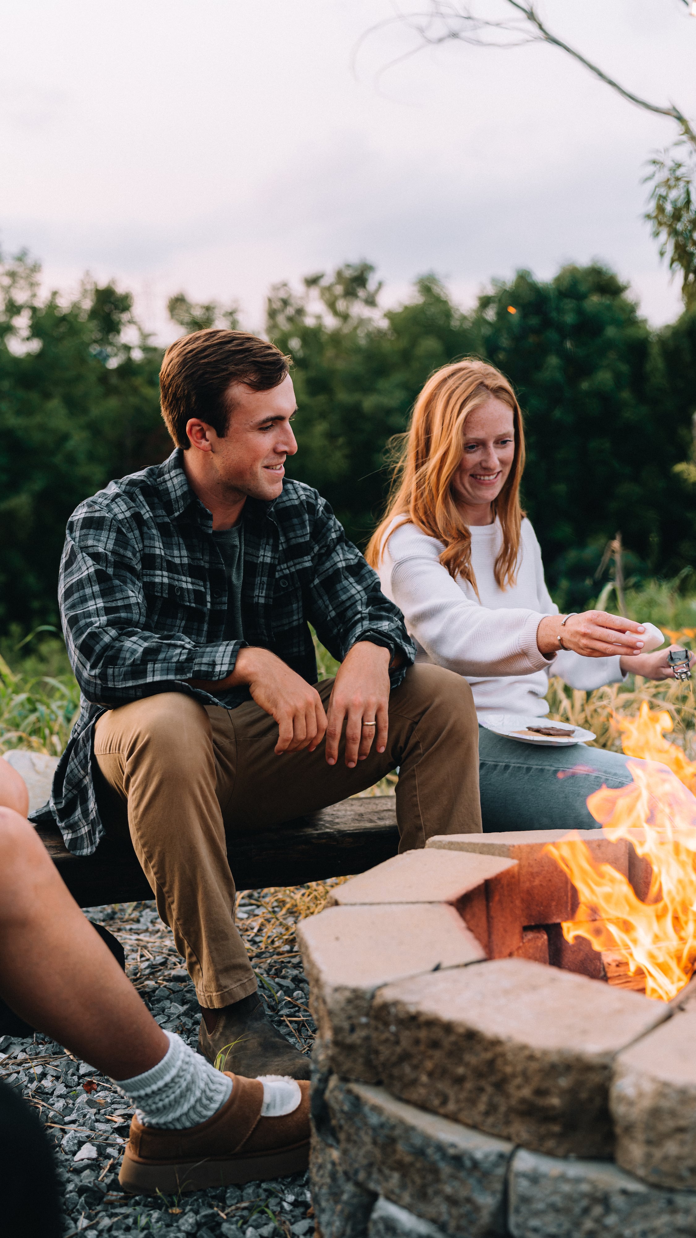A couple sitting close together beside the Sunset Point firepit at Sojourn Lodging