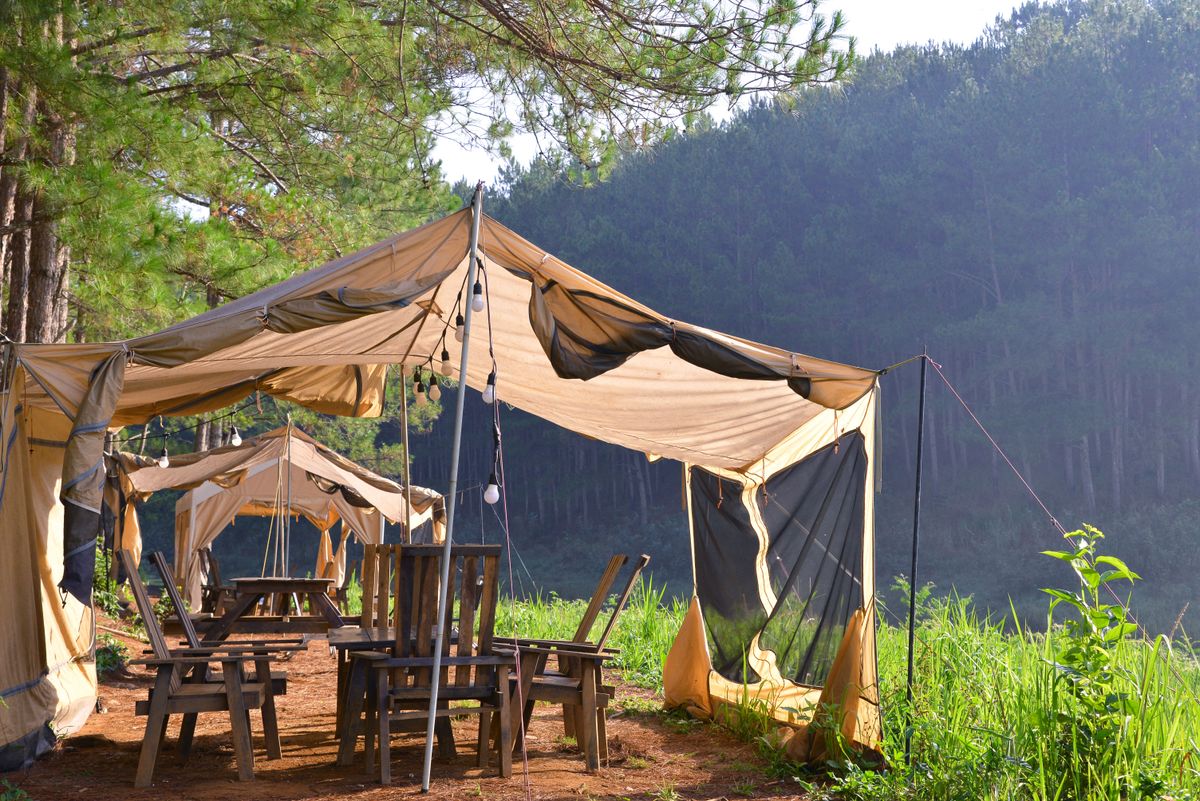 Safari tent accommodation set up underneath a green mountain view.