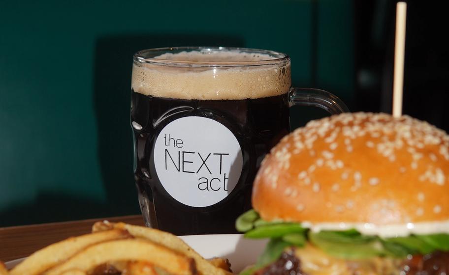 round graphic in black and white for Next Act Black beer featuring a jug of beer floating in water with theatre curtains