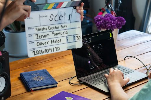 Person preparing music for release using a laptop and clapperboard