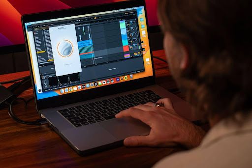 An artist mixing a song on a laptop