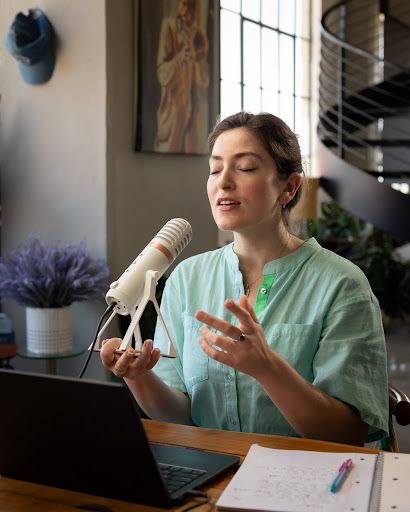 Woman recording vocals with a microphone and laptop