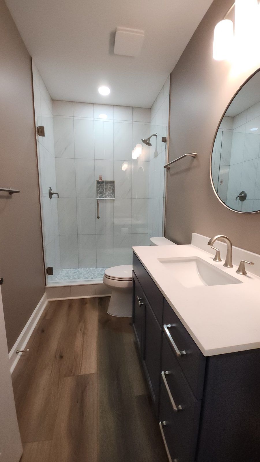 Renovated bathroom with vanity, framed mirror and walk-in shower