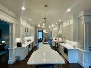 Bright white kitchen with marble island and chandelier