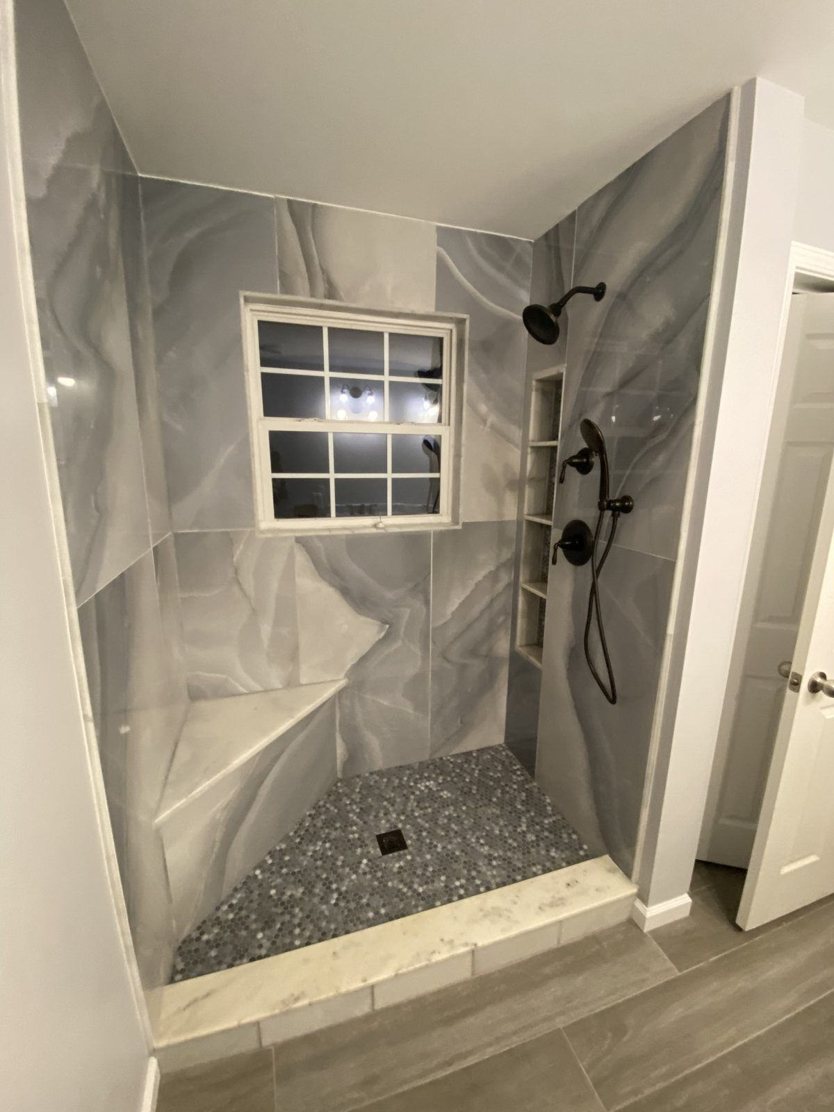 Marble walk-in shower with window and matte black fixtures