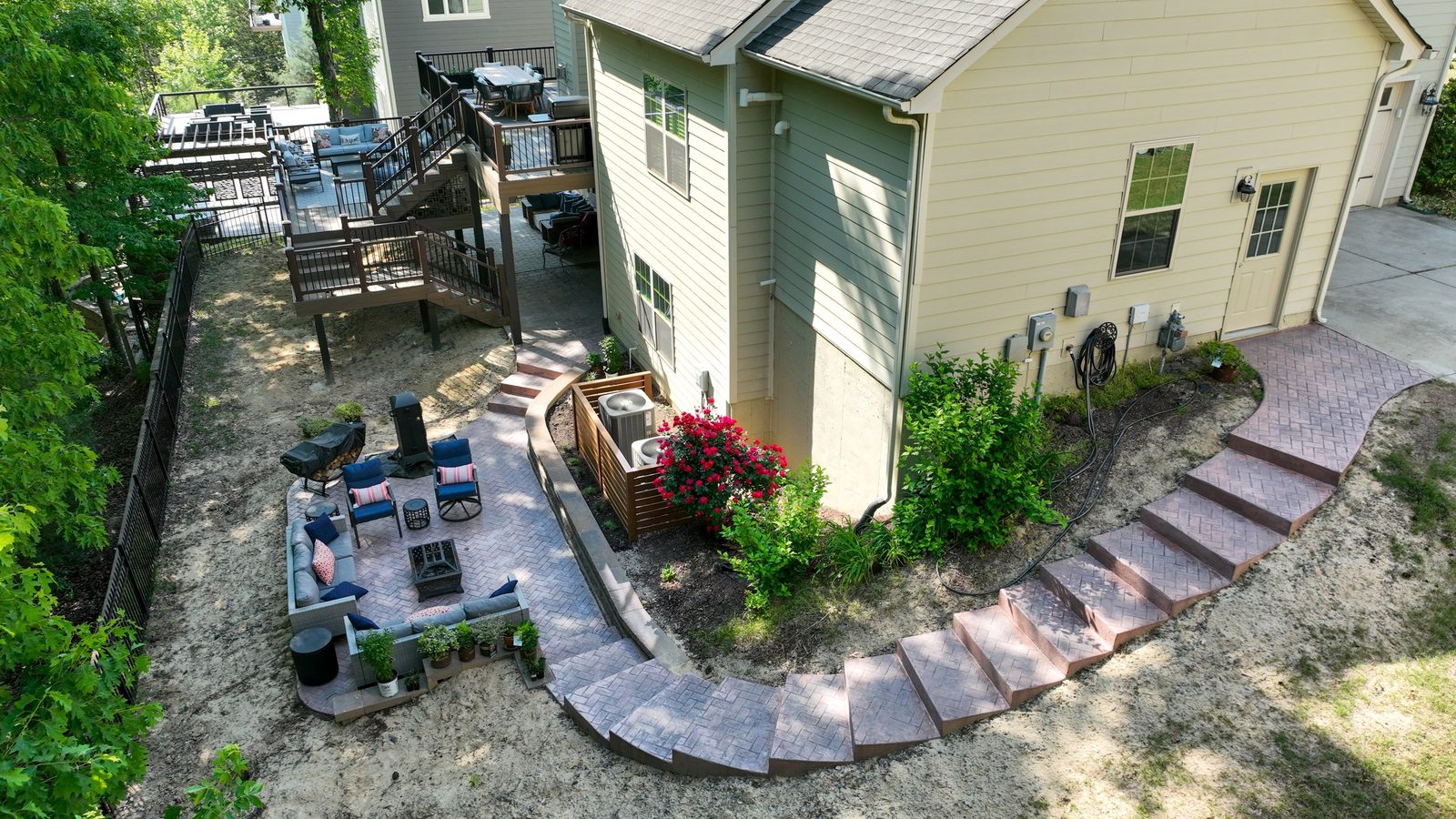 Aerial view of a landscaped backyard with paver walkway and fire pit