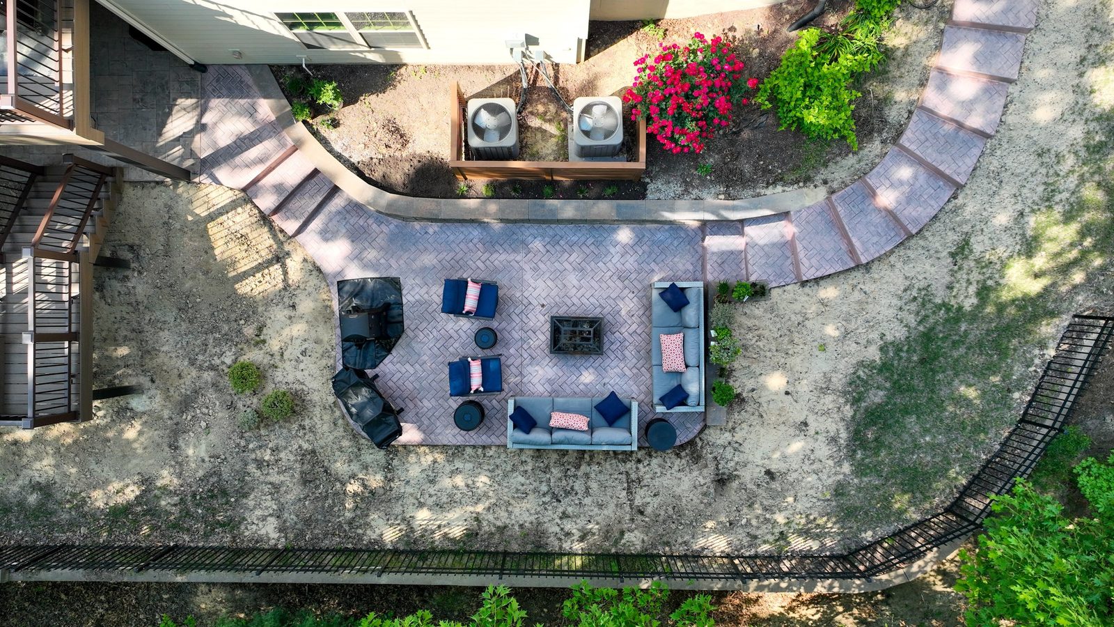 Aerial view of a curved paver patio with fire feature and lounge seating